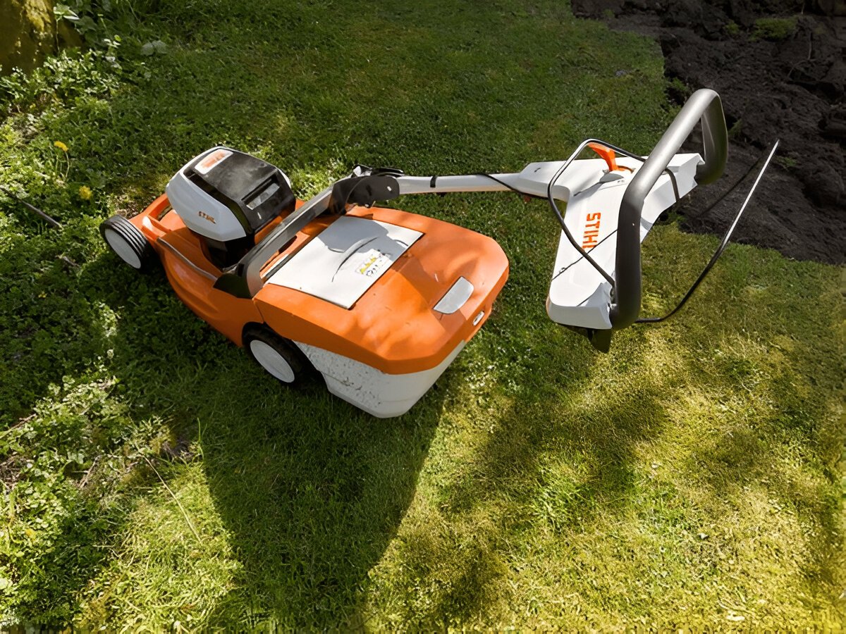 EGO, STIHL, and Makita cordless garden tools lined up on grass, ready for use in professional landscaping