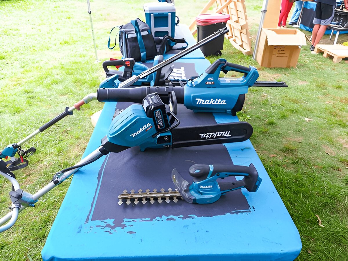 EGO, STIHL, and Makita cordless garden tools lined up on grass, ready for use in professional landscaping